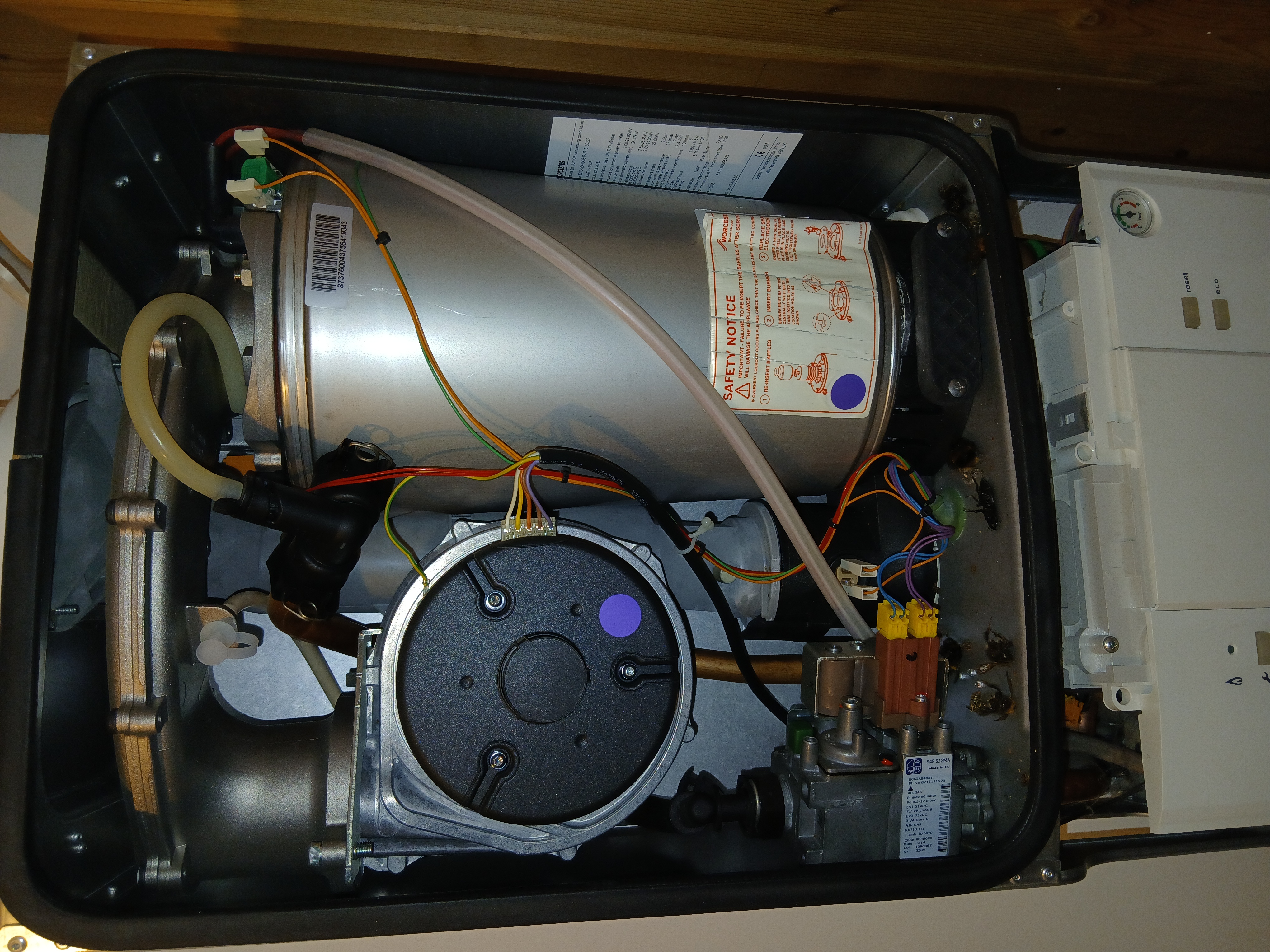 An open view of a boiler showing its internal components, wiring, and a safety notice on the side.